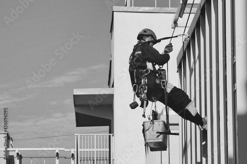 Industrial mountaineering worker hangs over residential facade building © Alex Vog
