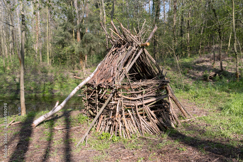 Handmade hut made of branches in the forest near pond on sunset. Handmade hut made of branches in the forest near pond on sunset.