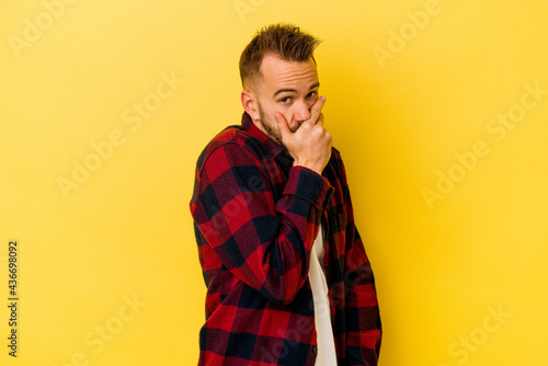 Young tattooed caucasian man isolated on yellow background scared and afraid.