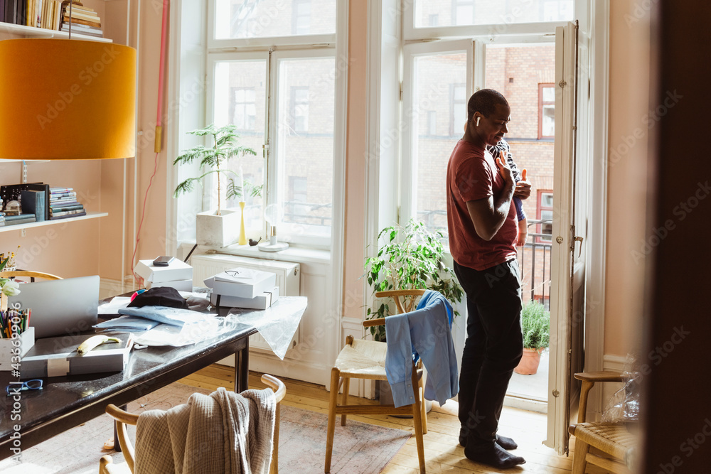 Businessman carrying baby boy while standing by door at home office Businessman carrying baby boy while standing by door at home office