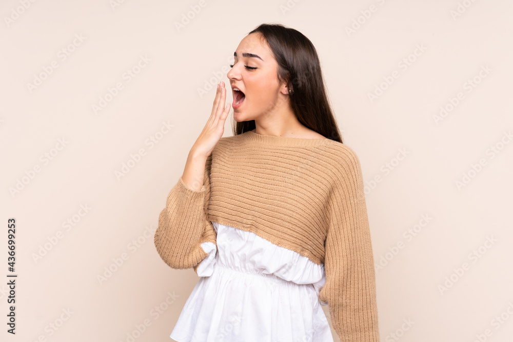 Young caucasian woman isolated on beige background yawning and covering wide open mouth with hand Young caucasian woman isolated on beige background yawning and covering wide open mouth with hand