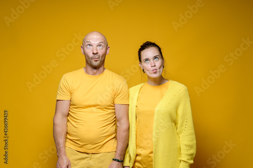 Strange man and woman in yellow robes, made stupid faces. Bright background.