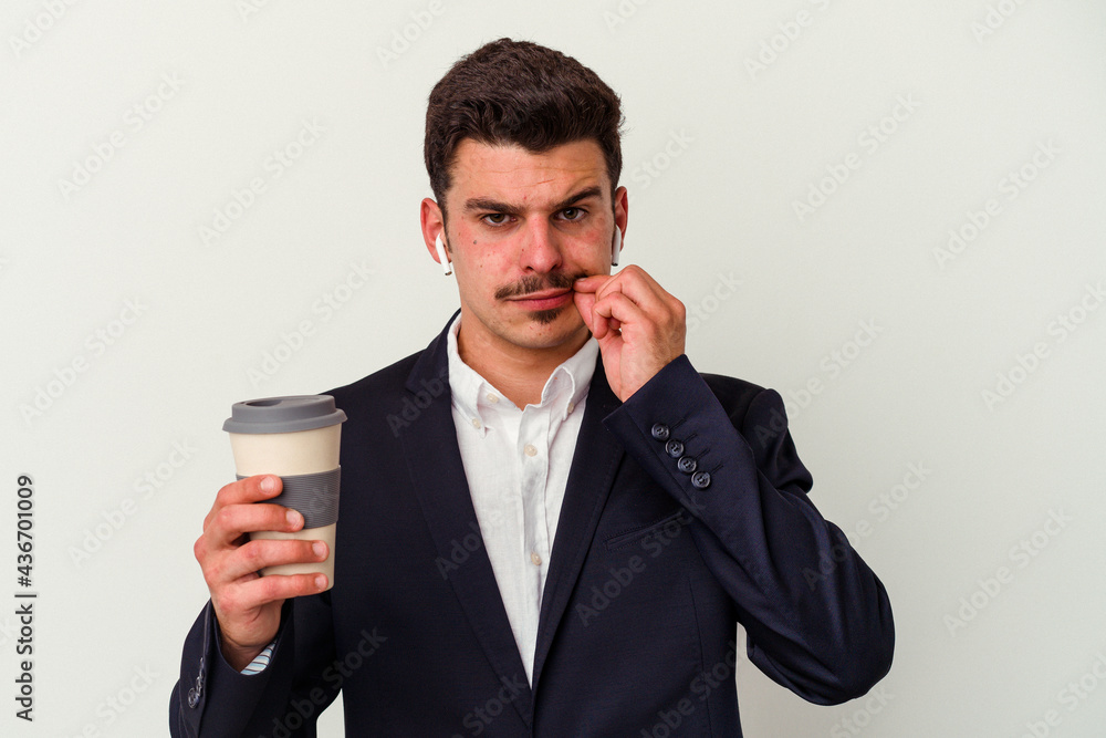Young business caucasian man wearing wireless headphones and holding take way coffee isolated on white background with fingers on lips keeping a secret. Young business caucasian man wearing wireless headphones and holding take way coffee isolated on white background with fingers on lips keeping a secret.