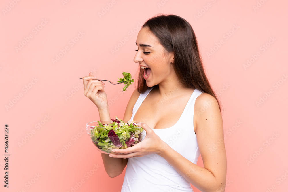 Young caucasian woman holding a salad isolated on pink background Young caucasian woman holding a salad isolated on pink background