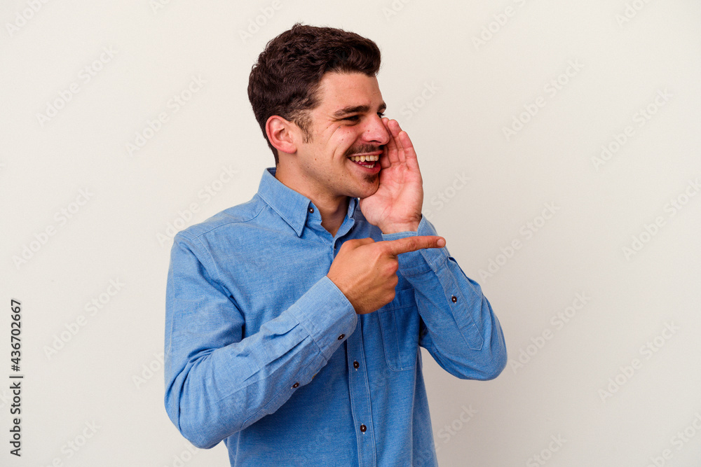 Young caucasian man isolated on white background saying a gossip, pointing to side reporting something. Young caucasian man isolated on white background saying a gossip, pointing to side reporting something.