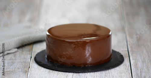 The mousse cake is decorated with chocolate mirror glaze. Modern dessert.