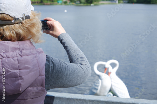 A girl in a white cap takes pictures of the water landscape with a camera. St. Veronica's Day Photographer's Day . photo