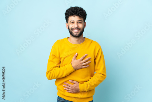Young Moroccan man isolated on blue background smiling a lot