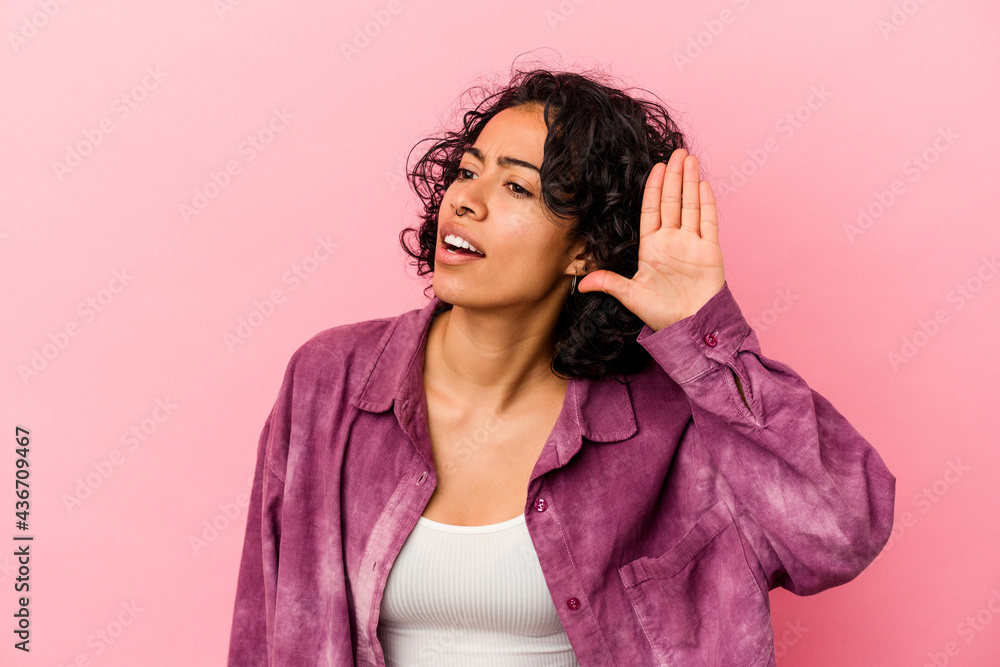 Young curly latin woman isolated on pink background trying to listening a gossip. Young curly latin woman isolated on pink background trying to listening a gossip.