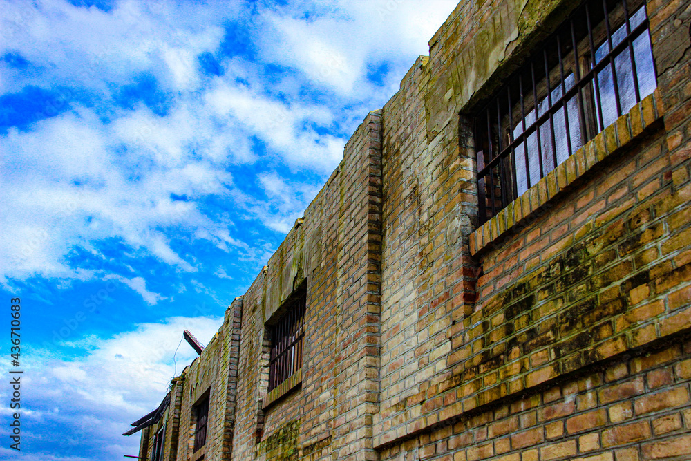 old abandoned wall with barred windows and sky
