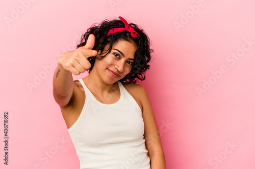 Young curly latin woman isolated on pink background cheerful smiles pointing to front.