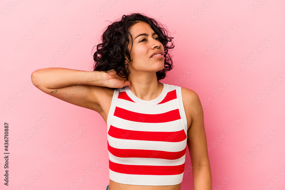 Young curly latin woman isolated on pink background having a neck pain due to stress, massaging and touching it with hand. Young curly latin woman isolated on pink background having a neck pain due to stress, massaging and touching it with hand.