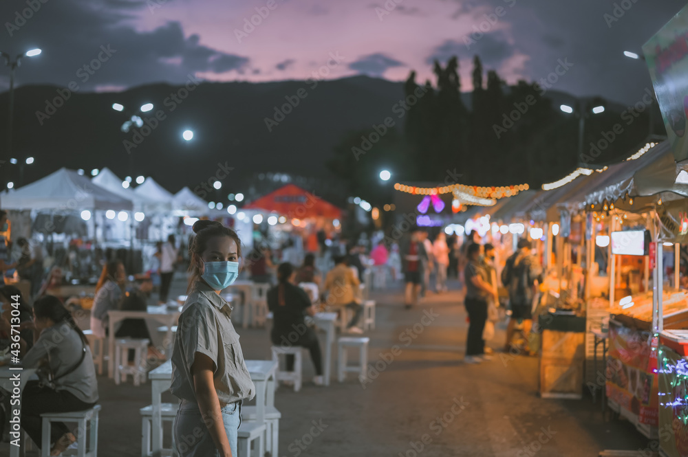 Obraz premium Young women wearing surgical mask touring in night market , Chaing Mai Thailand