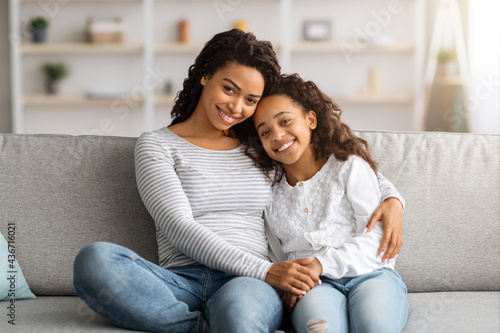 Cheerful african american mother and daughter posing at home