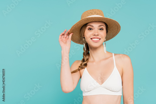 Smiling woman in sun hat and top isolated on blue.