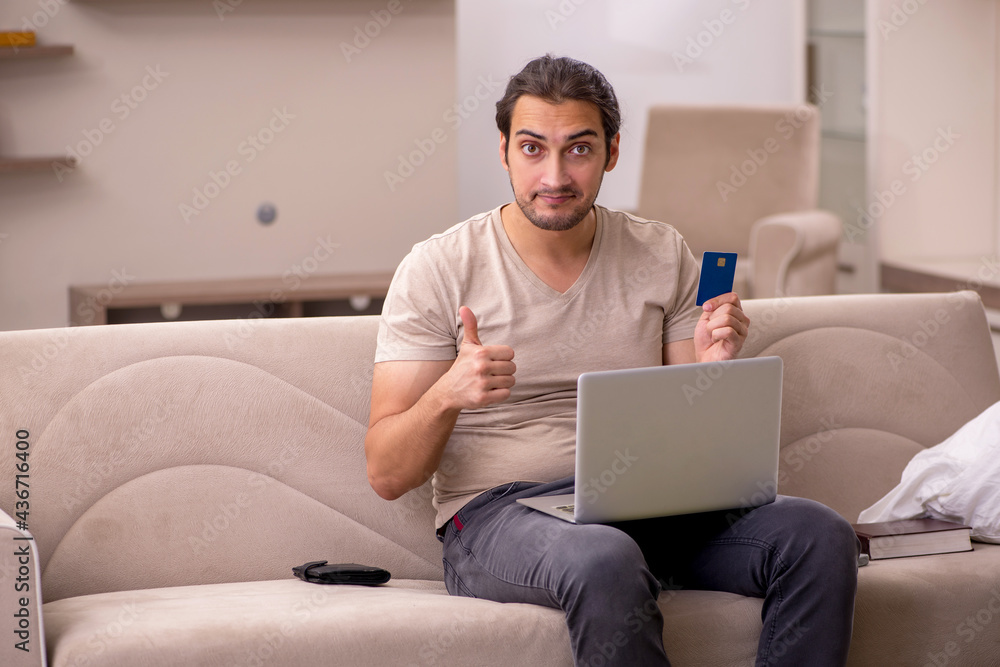 Young man ordering goods by credit card at home Young man ordering goods by credit card at home