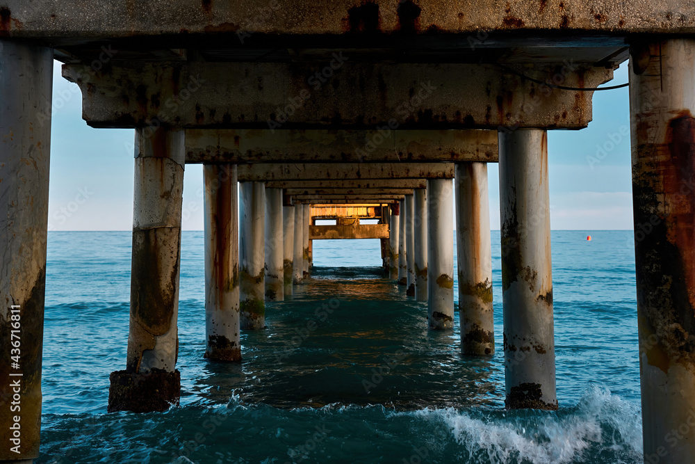 Under a pier, clear turquoise water of the mediterranean Sea.