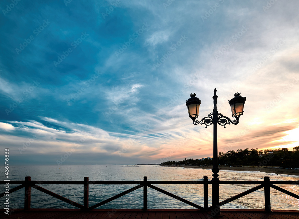 Sunset life from jetty in Marbella, Costa del Sol, Spain. Street lamps