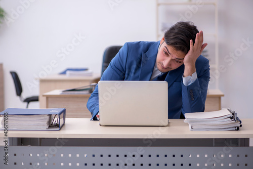 Young male employee being unhappy with excessive work