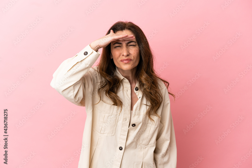 Middle aged caucasian woman isolated on pink background looking far away with hand to look something Middle aged caucasian woman isolated on pink background looking far away with hand to look something