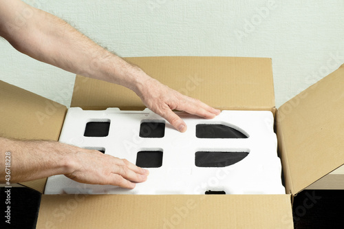 Male hands place the foam sealant in a cardboard box. Concept delivery, packaging