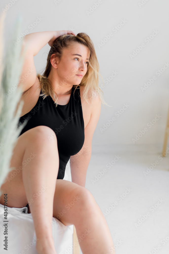 body positive. A woman in black underwear poses on a modern white interior body positive. A woman in black underwear poses on a modern white interior