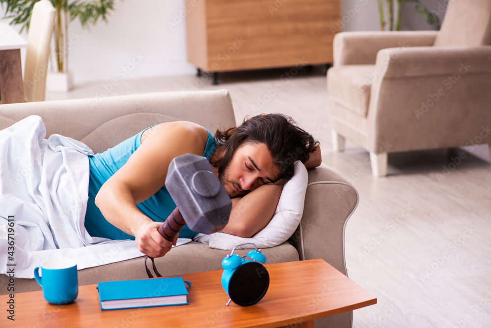 Young man lying on the sofa in time management concept Young man lying on the sofa in time management concept