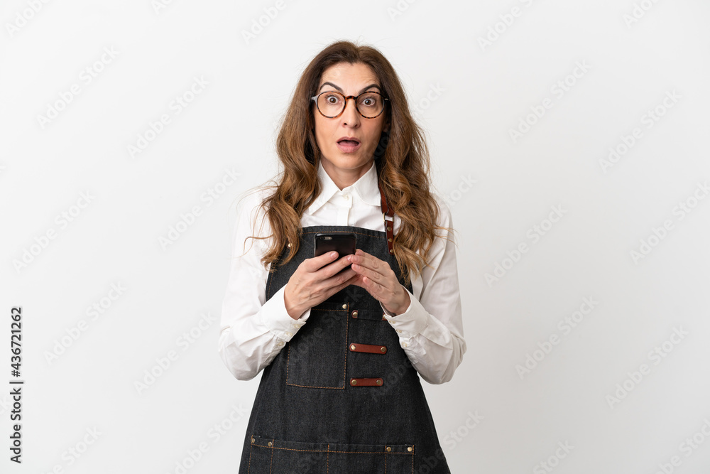 Restaurant middle aged waiter woman isolated on white background surprised and sending a message Restaurant middle aged waiter woman isolated on white background surprised and sending a message