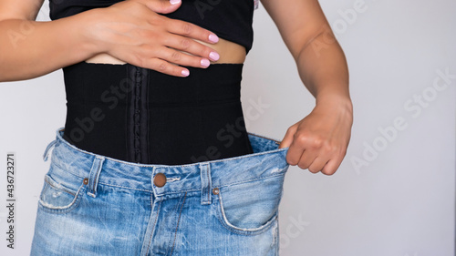Quadro em tela A woman fastens a corset for figure correction