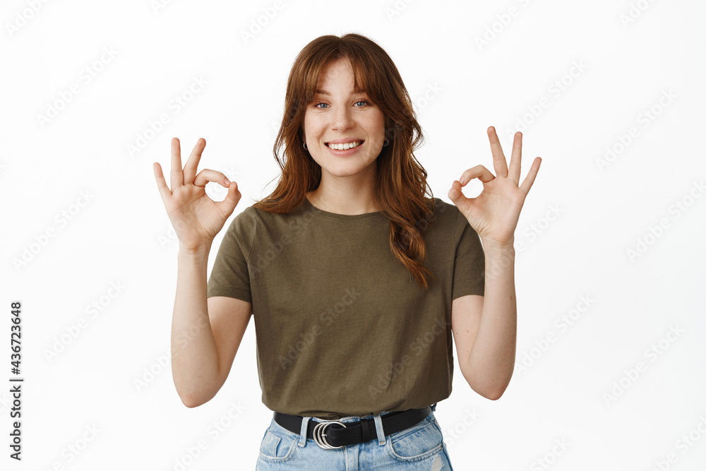 Very well, good job. Smiling young woman showing Okay ok gesture, nod in approval, say yes, agree with your choice, praise great thing, standing over white background Very well, good job. Smiling young woman showing Okay ok gesture, nod in approval, say yes, agree with your choice, praise great thing, standing over white background
