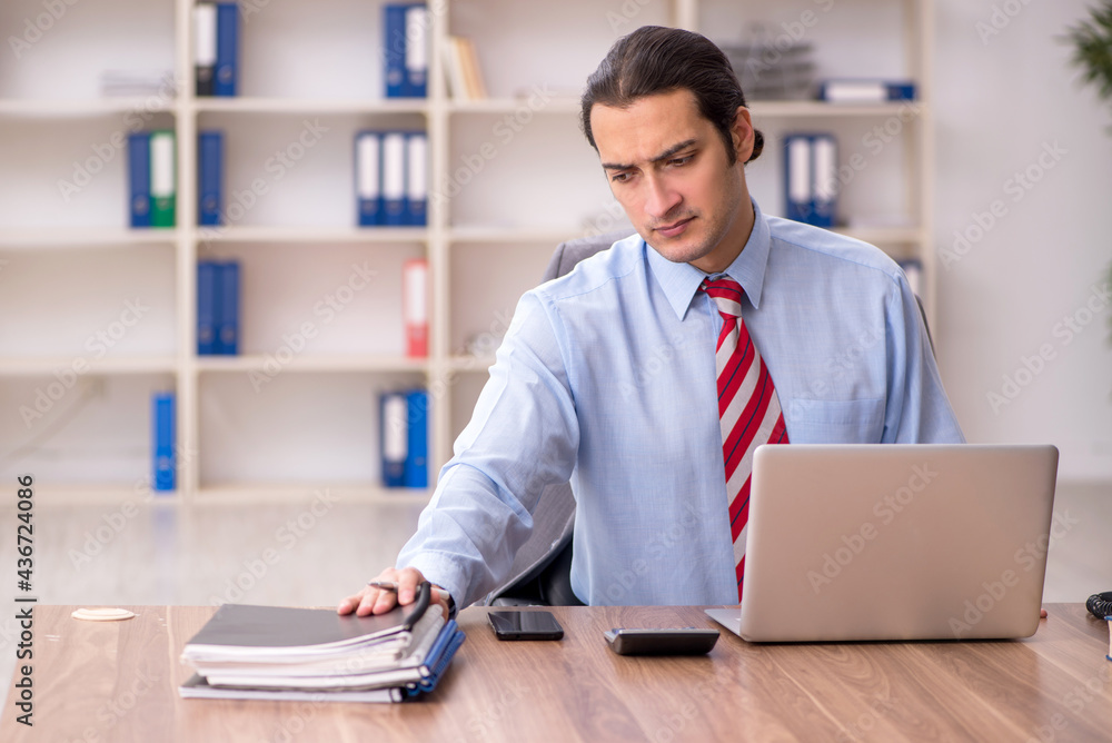 Young male employee sitting at workplace Young male employee sitting at workplace