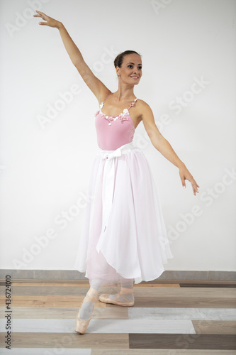 Beautiful professional ballerina in pink dress dance in ballet studio