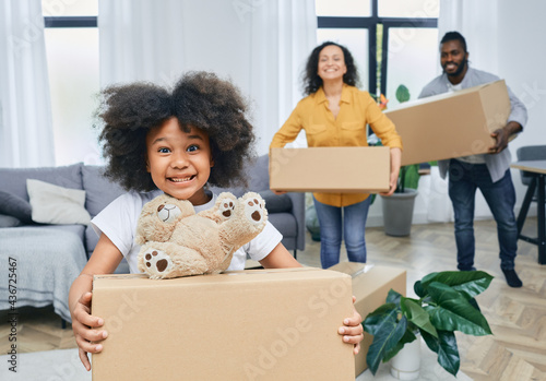 Happy African American family with cardboard boxes and things moves to a new home. Buying or renting a house for a young family