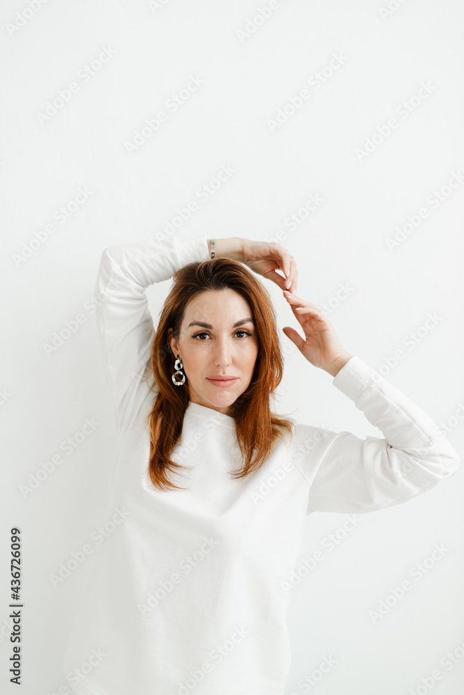 Fototapeta premium b girl in a white sweater holds her hands above her head