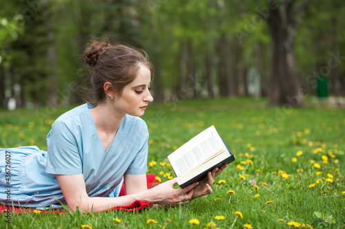 Young beautiful woman with a book resting in a summer park