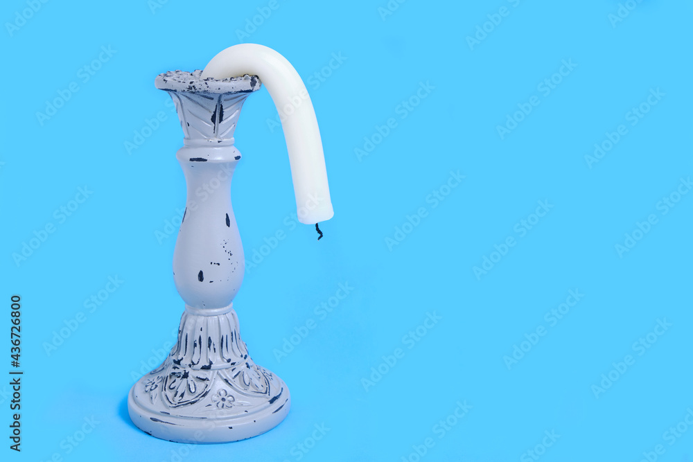 Candle Holder with a Drooping Candle on a Blue Background Concept Impotence Impotence and Old Age in Sex - obrazy, fototapety, plakaty 