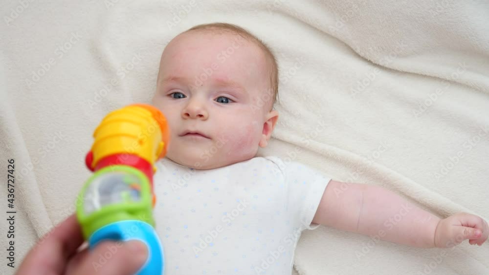 POV shot of parent playing with colorful plastic toy with little baby son lying in bed. Concept of baby education and development POV shot of parent playing with colorful plastic toy with little baby son lying in bed. Concept of baby education and development