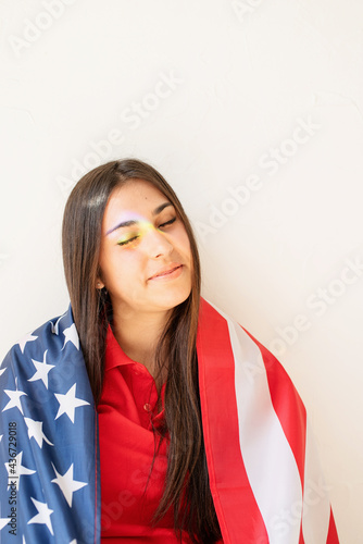 beautiful young woman with american flag and rainbow reflection on the face
