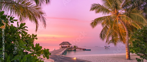 Fototapeta Naklejka Na Ścianę i Meble -  Amazing sunset panorama at Maldives. Luxury resort villas seascape, soft led lights under romantic colorful sky and palm tree leaves. Stunning travel beach landscape exotic relax vacation resort hotel