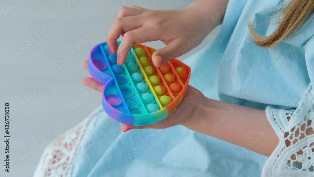 Child playing with rainbow pop it fidget toy. Push bubble fidget sensory toy - washable and reusable silicon stress relief toy. Antistress toy for child with special needs. Child playing with rainbow pop it fidget toy. Push bubble fidget sensory toy - washable and reusable silicon stress relief toy. Antistress toy for child with special needs.