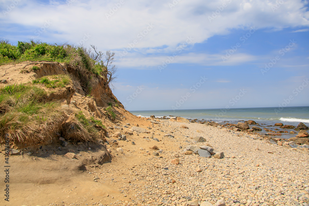 Beach with rocks and a sand dune near the ocean in summer