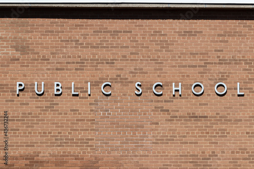 PUBLIC SCHOOL in stainless steel text against a brick background. photo
