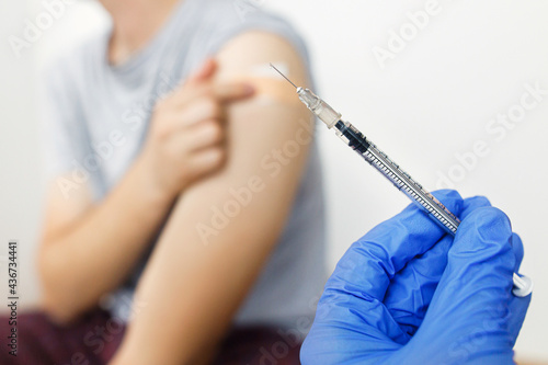 Syringe with vaccine in doctor hand on background of man holding arm with adhesive bandage after coronavirus vaccine injection. Coronavirus Vaccination. Covid-19 immunization program