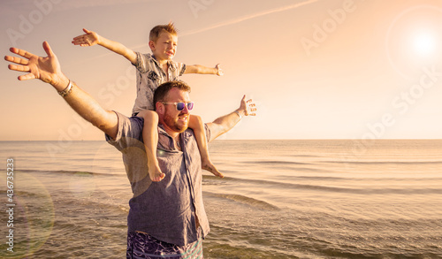 dad with son on his shoulders looking at the horizon in the water at the sea