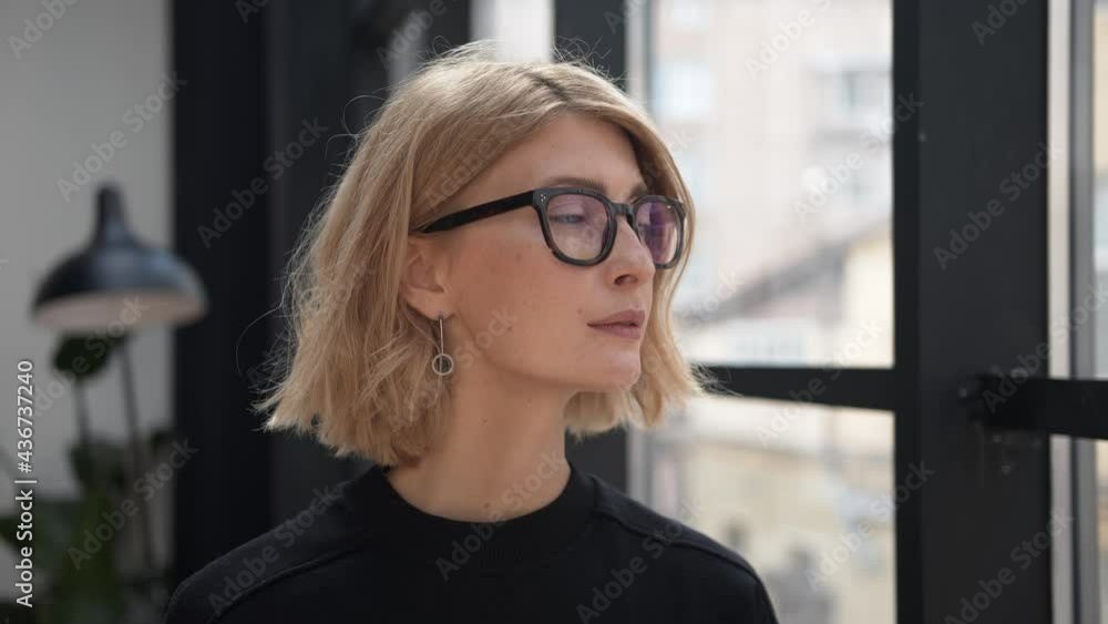 Boss woman in eyeglasses, attractive blonde manager profile portrait thinking and looking out the window. Office room and worker in black clothes. Concept of business partner Boss woman in eyeglasses, attractive blonde manager profile portrait thinking and looking out the window. Office room and worker in black clothes. Concept of business partner