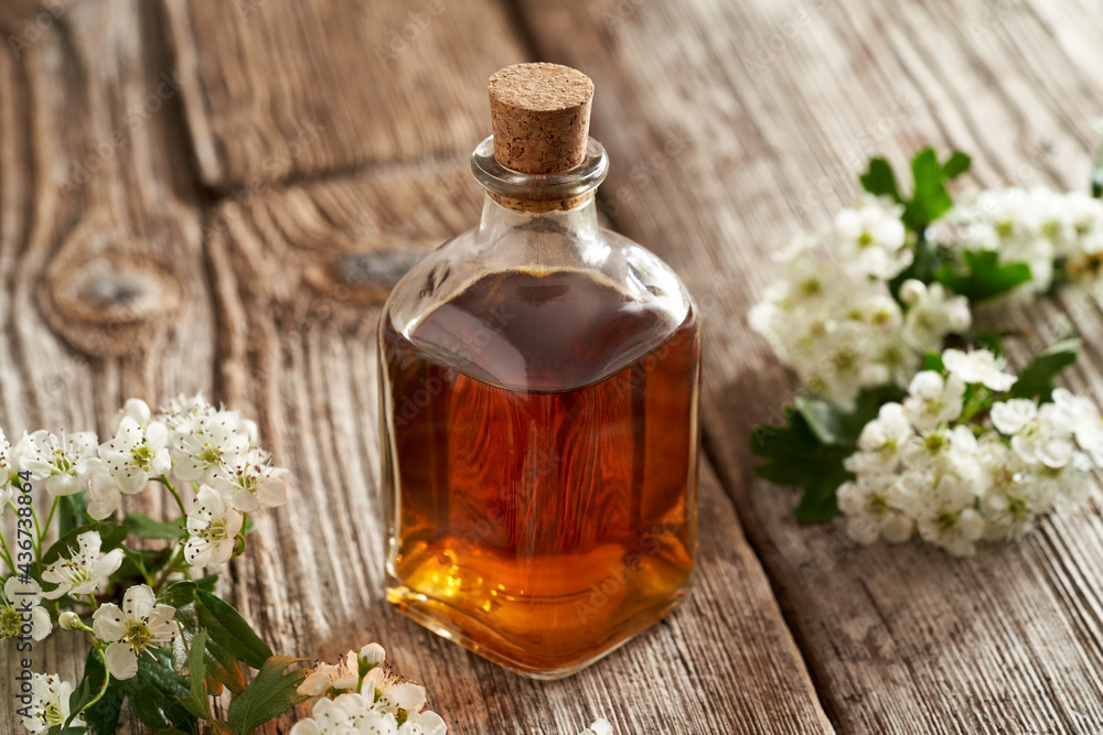A bottle of hawthorn tincture with blooming hawthorn branches A bottle of hawthorn tincture with blooming hawthorn branches