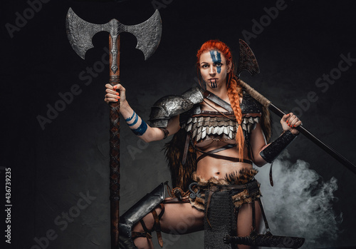 Scandinavian barbaric woman with redhairs holding two axes in smoke