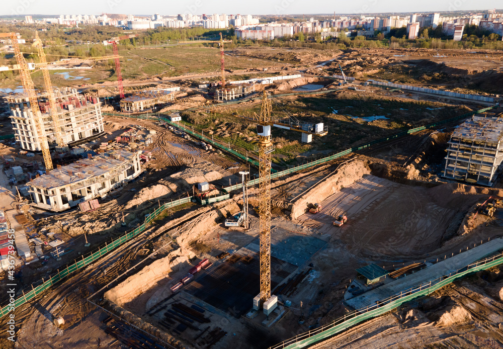 Tower cranes in action at construction site. Crane during formworks. Soil Compactor leveling ground for construct of foundation for residential building. Construction Foundation in pit. Out of focus