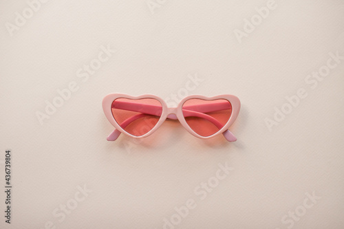 Layout. Pink glasses in the form of hearts on a light pink background. Summer. High quality photo