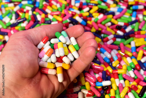 Multicolored pills in capsules in hand. Pharmaceutical pill for medical. Medical pill for maintaining and improving health. Concept of healthcare and medicine
